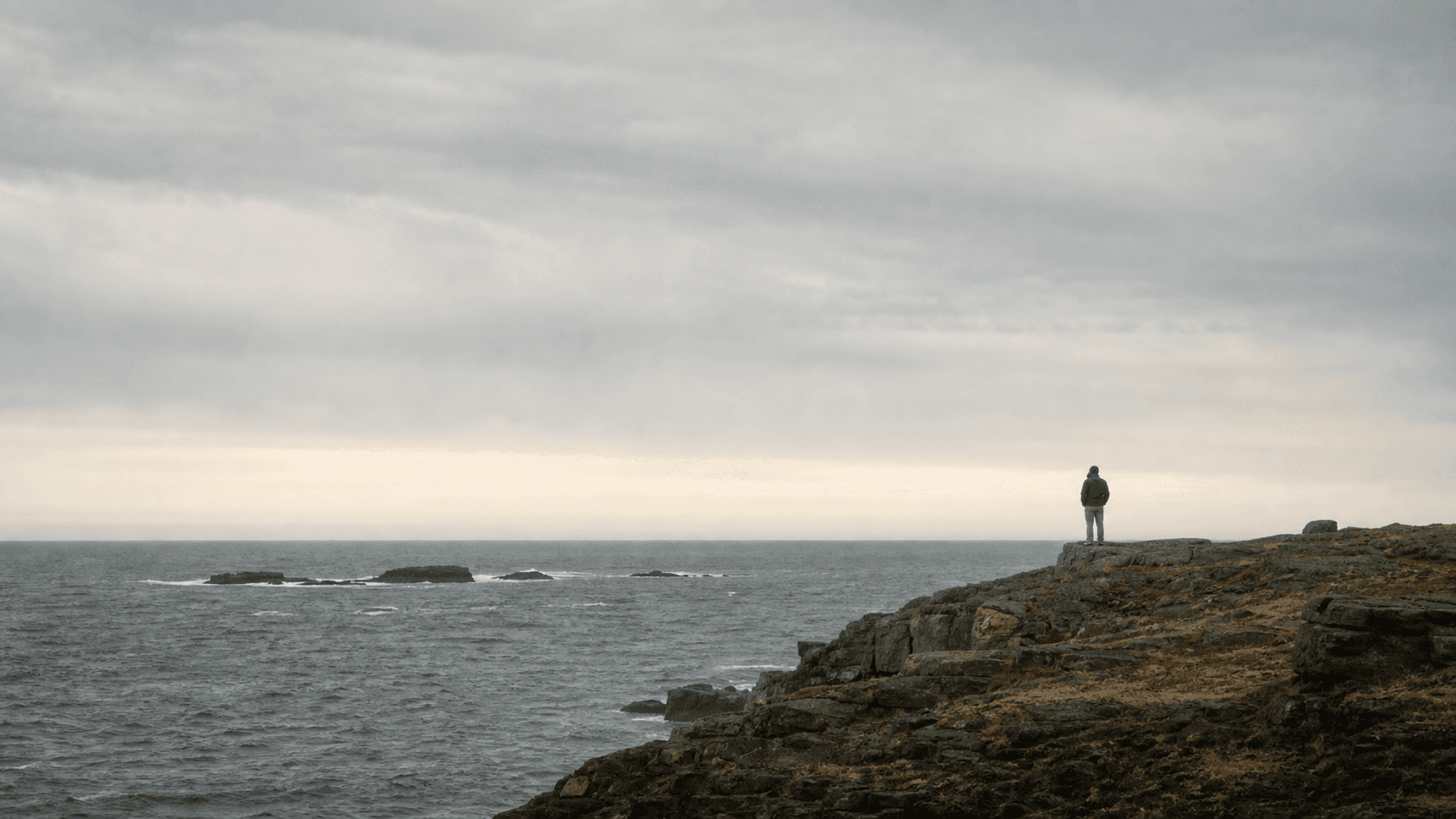 A solitary figure looking across a rugged Atlantic coastline